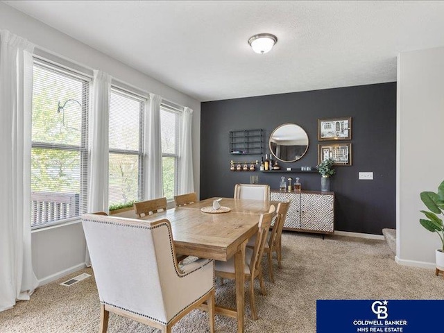 carpeted dining room featuring baseboards and visible vents