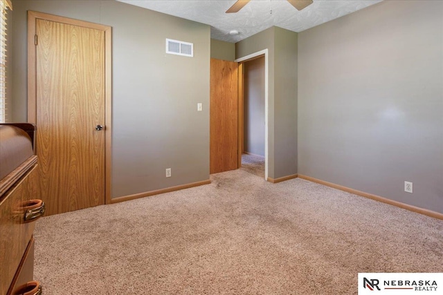 unfurnished bedroom featuring carpet floors, baseboards, a ceiling fan, and visible vents