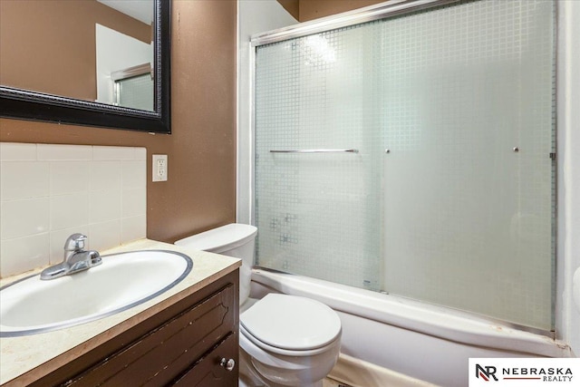 full bath with shower / bath combination with glass door, backsplash, toilet, and vanity