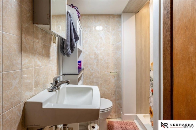 bathroom featuring toilet, tile walls, and a sink
