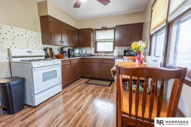 kitchen with ceiling fan, black microwave, tasteful backsplash, light wood-type flooring, and white range with gas cooktop