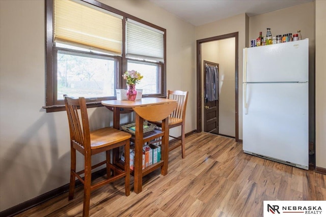 dining area featuring plenty of natural light, light wood finished floors, and baseboards