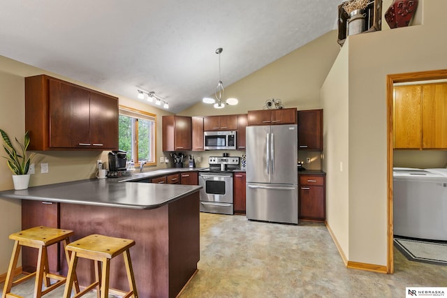 kitchen with washer / clothes dryer, stainless steel appliances, dark countertops, and a peninsula