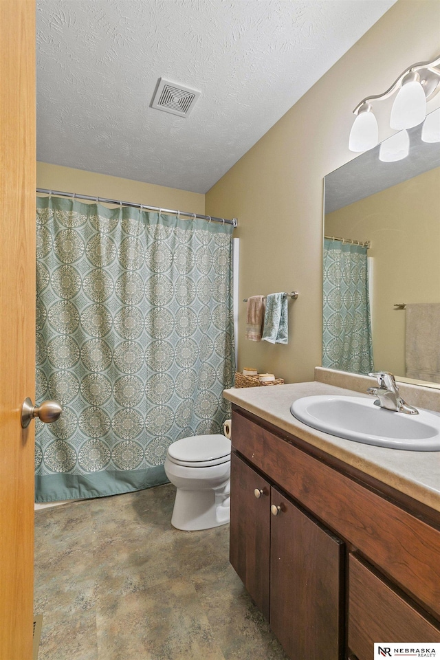 full bathroom with visible vents, vanity, toilet, a textured ceiling, and stone finish flooring