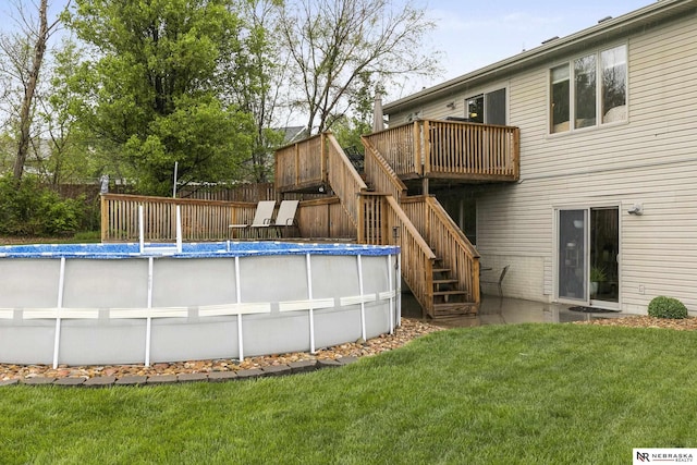 exterior space featuring a wooden deck, fence, an outdoor pool, a yard, and stairway
