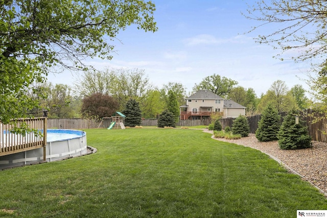 view of yard featuring a fenced in pool, a fenced backyard, and a playground