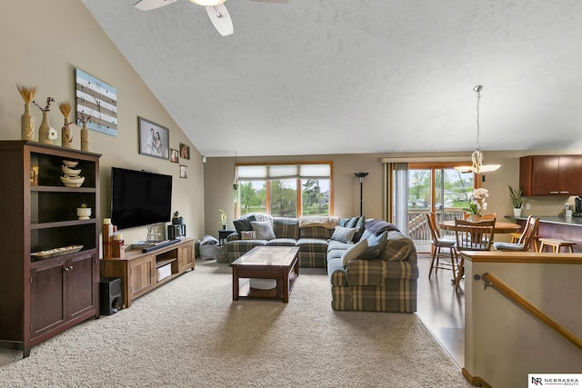 living room featuring vaulted ceiling, ceiling fan with notable chandelier, a healthy amount of sunlight, and light carpet