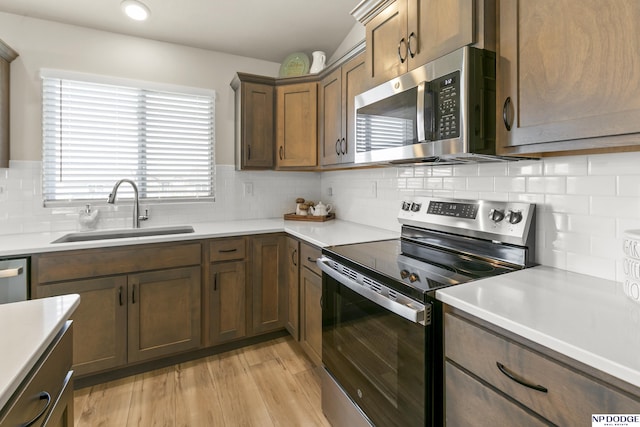 kitchen featuring a sink, light wood finished floors, appliances with stainless steel finishes, and light countertops