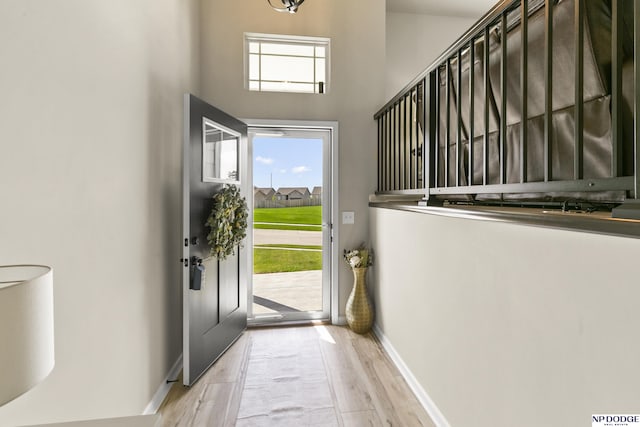 entryway featuring baseboards, a high ceiling, and wood finished floors