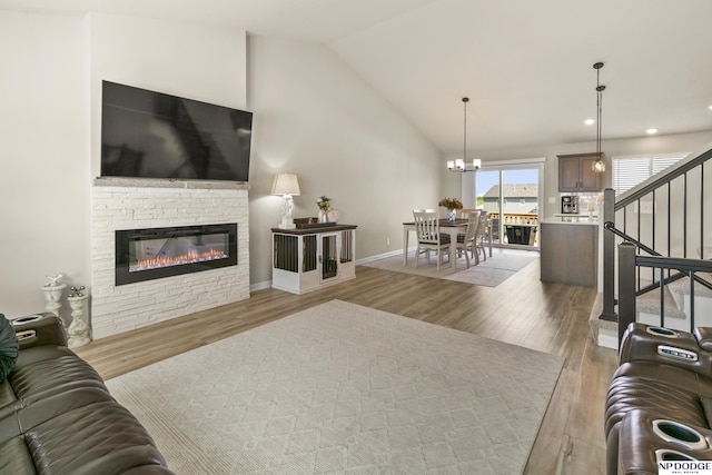living area featuring a stone fireplace, vaulted ceiling, wood finished floors, stairway, and an inviting chandelier