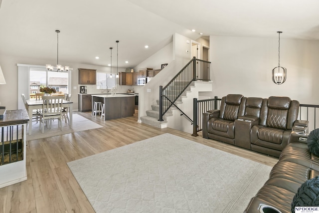 living area with stairs, light wood-style flooring, and a notable chandelier
