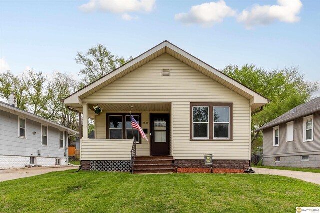 bungalow-style home featuring covered porch and a front lawn