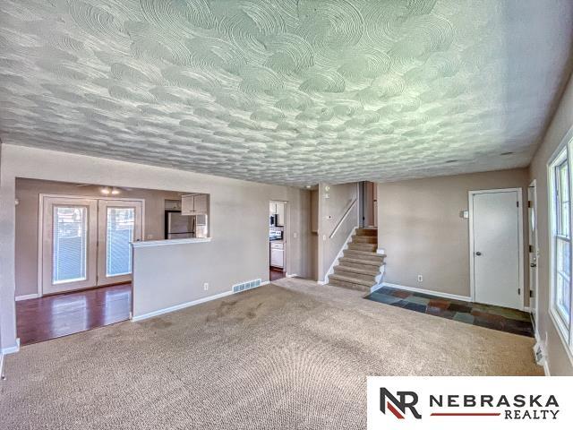 unfurnished living room featuring baseboards, plenty of natural light, carpet flooring, and visible vents