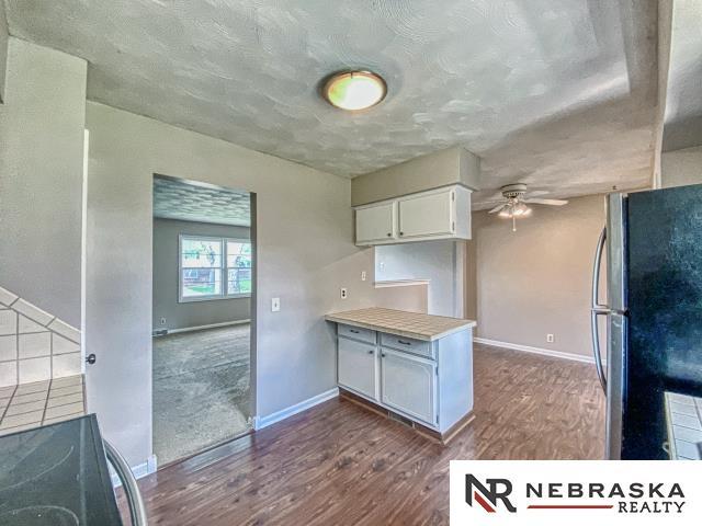 kitchen featuring ceiling fan, freestanding refrigerator, dark wood-style floors, and white cabinetry