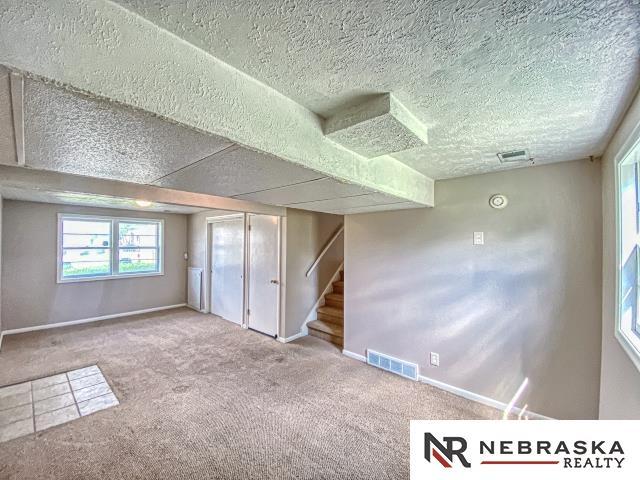 basement with baseboards, carpet, stairs, and visible vents