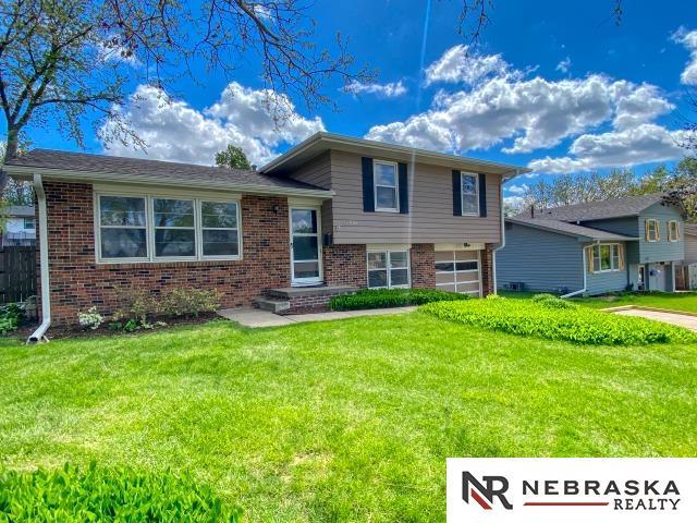 split level home with a garage, a front lawn, and brick siding