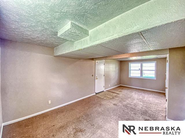 below grade area with carpet floors, a textured ceiling, and baseboards