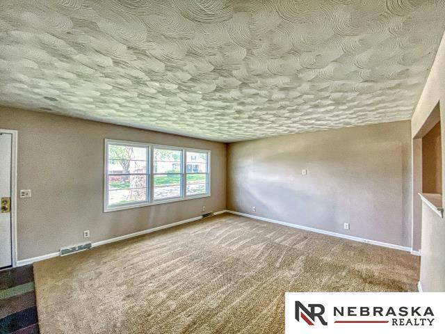 carpeted spare room with baseboards, a textured ceiling, and visible vents