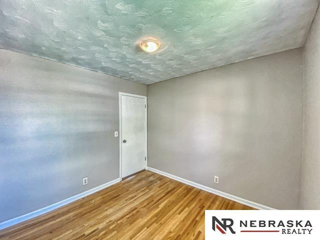 unfurnished room with baseboards, a textured ceiling, and wood finished floors