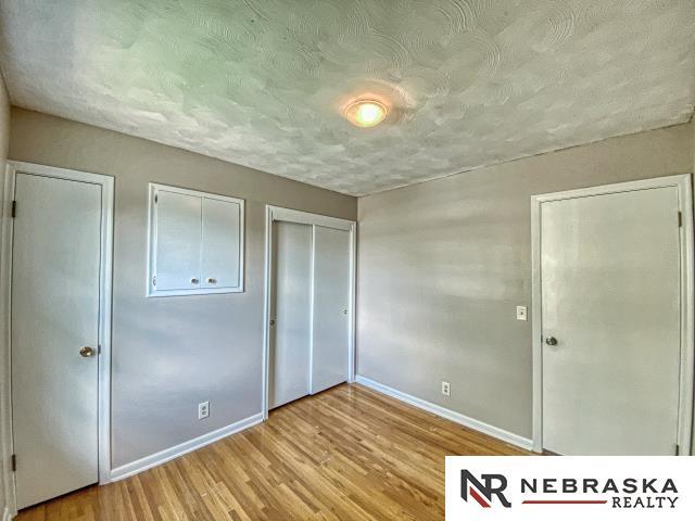 unfurnished bedroom featuring baseboards, a textured ceiling, and wood finished floors