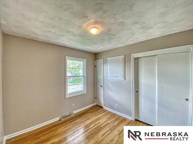 unfurnished bedroom with a textured ceiling, visible vents, baseboards, a closet, and light wood-style floors