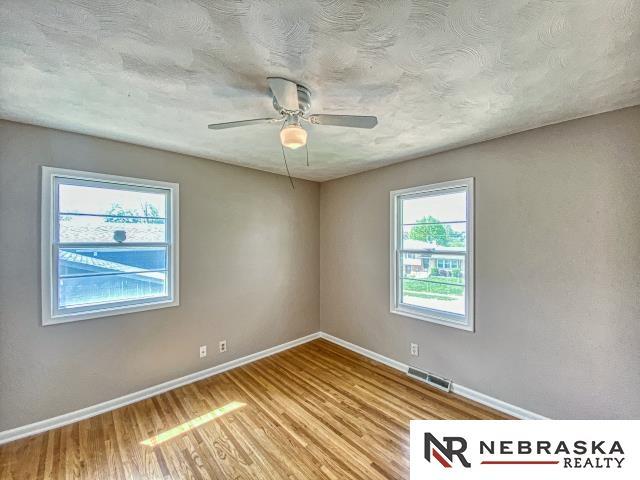 spare room with a ceiling fan, baseboards, visible vents, and wood finished floors