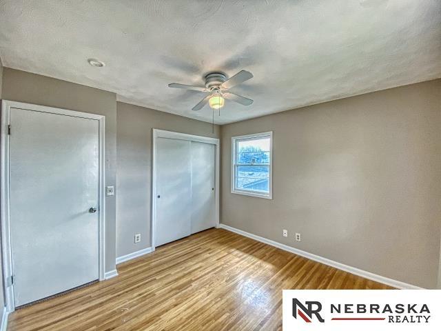 unfurnished bedroom with a ceiling fan, baseboards, wood finished floors, and a closet