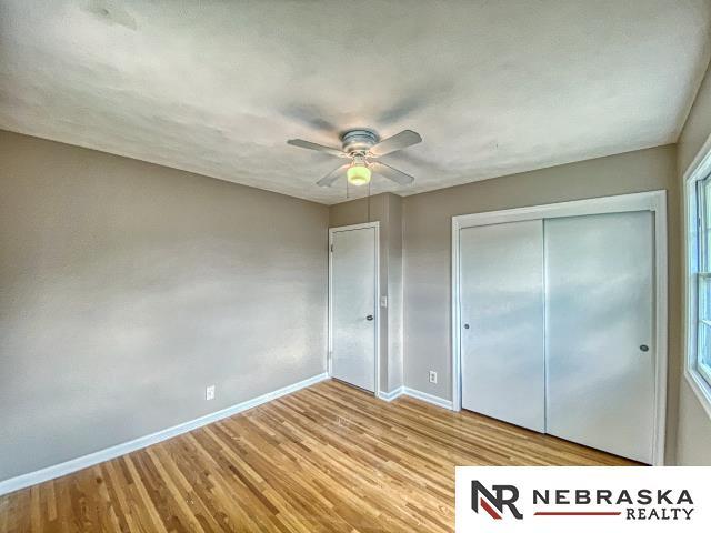 unfurnished bedroom featuring baseboards, a ceiling fan, wood finished floors, and a closet