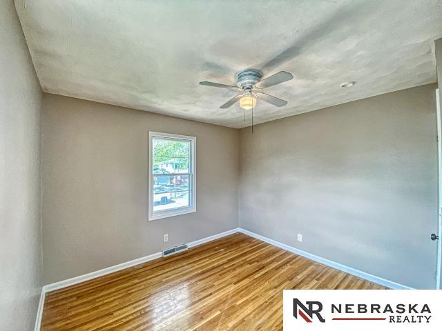 unfurnished room featuring baseboards, ceiling fan, visible vents, and wood finished floors