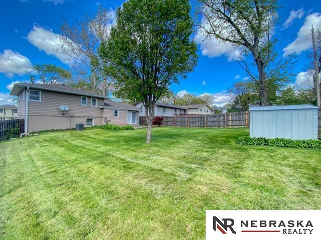 view of yard featuring an outdoor structure, central air condition unit, fence, and a storage shed