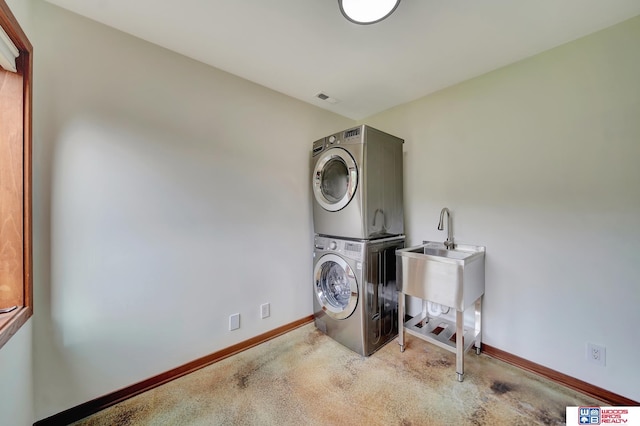 washroom featuring laundry area, stacked washer and dryer, a sink, baseboards, and carpet floors