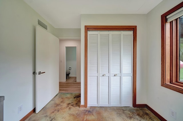 unfurnished bedroom with baseboards, a closet, light colored carpet, and visible vents