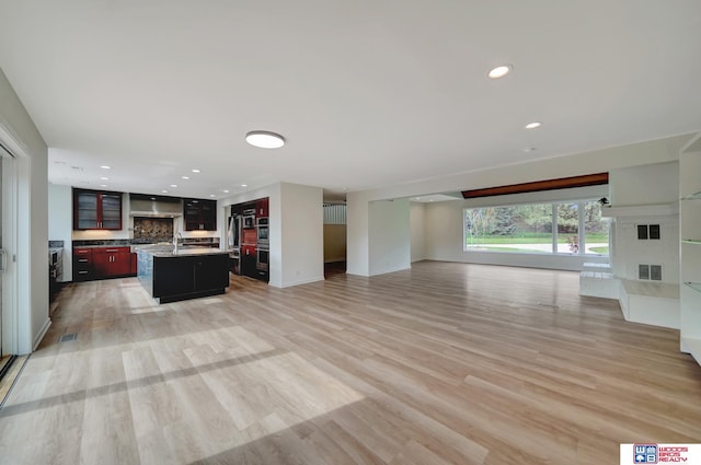 unfurnished living room with light wood-type flooring, a fireplace with raised hearth, recessed lighting, and visible vents
