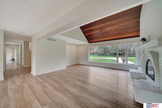 unfurnished living room with visible vents, lofted ceiling, a fireplace, baseboards, and light wood-style flooring