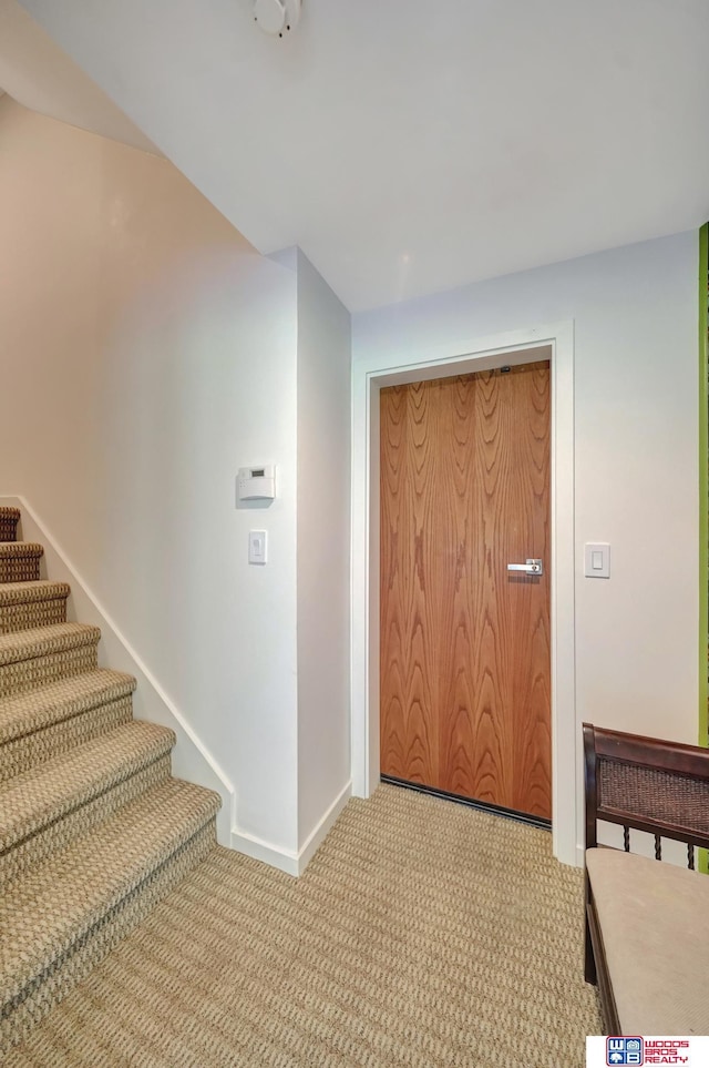 entrance foyer with stairway, baseboards, and light colored carpet