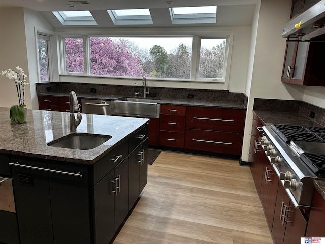 kitchen with under cabinet range hood, a skylight, plenty of natural light, and a sink