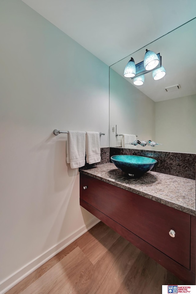 bathroom with baseboards, vanity, wood finished floors, and visible vents