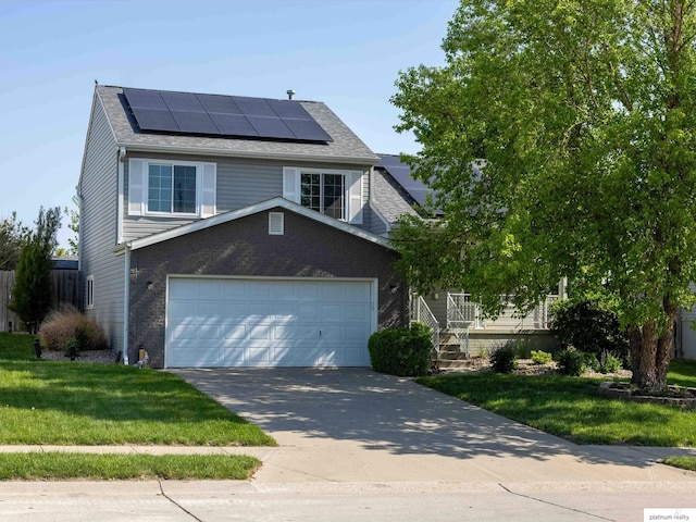 traditional-style home featuring an attached garage, roof mounted solar panels, a front yard, and driveway