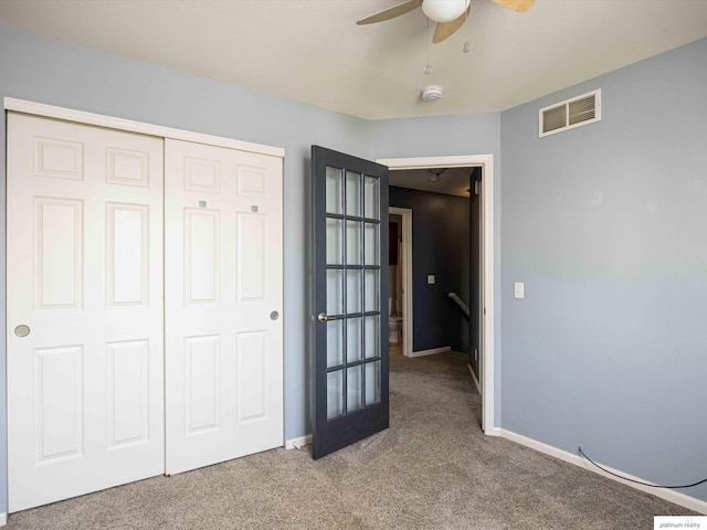 unfurnished bedroom with carpet floors, a closet, baseboards, and a ceiling fan