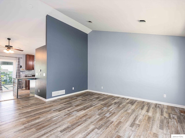 unfurnished living room with wood finished floors, baseboards, ceiling fan, and lofted ceiling