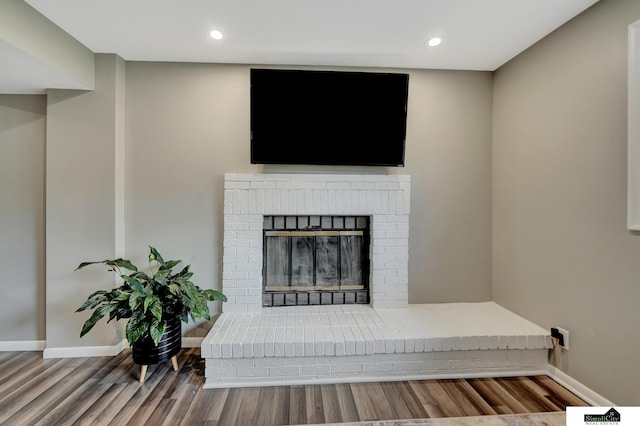 living room featuring baseboards, a fireplace, recessed lighting, and wood finished floors