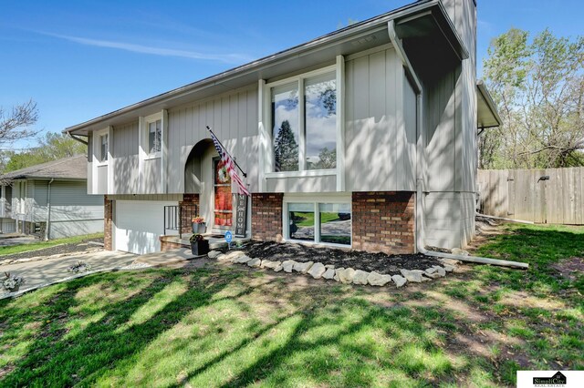 split foyer home with a front lawn, fence, brick siding, concrete driveway, and an attached garage