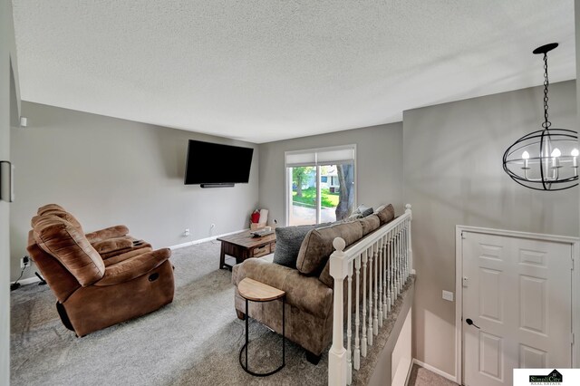carpeted living room featuring a textured ceiling, an inviting chandelier, and baseboards