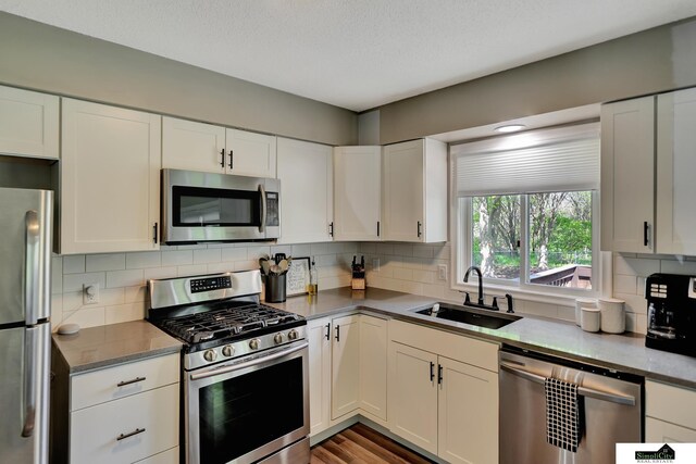 kitchen with a sink, decorative backsplash, white cabinets, and stainless steel appliances