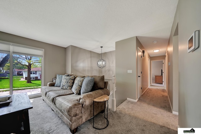 carpeted living area with baseboards, a textured ceiling, and a notable chandelier