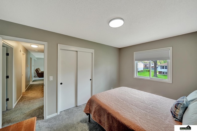 bedroom with a closet, a textured ceiling, carpet, and baseboards