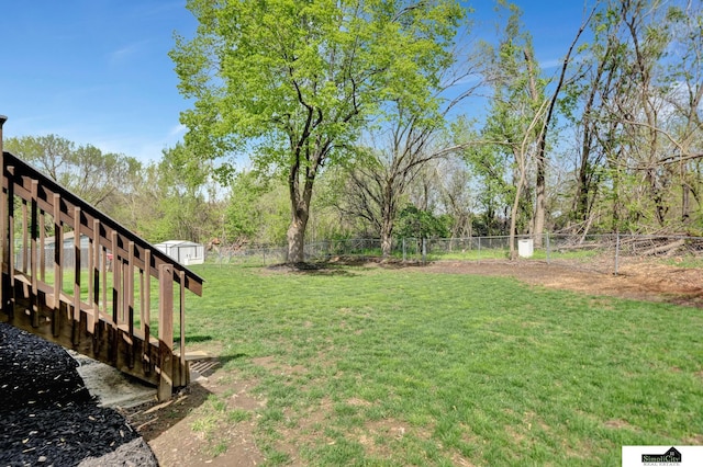 view of yard with an outdoor structure, a fenced backyard, and a shed