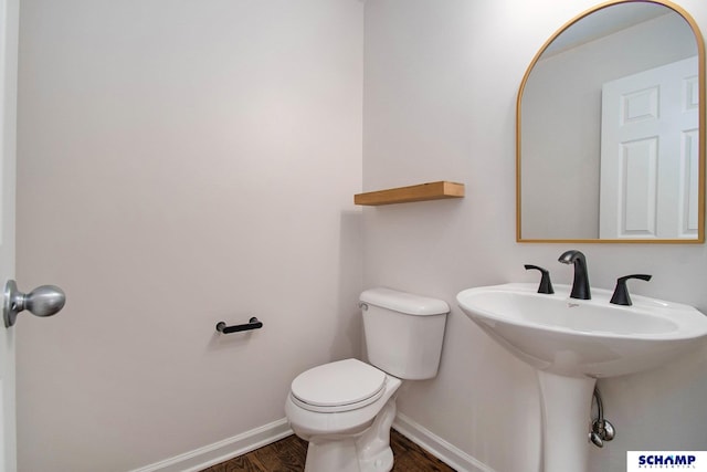 bathroom with wood finished floors, baseboards, toilet, and a sink