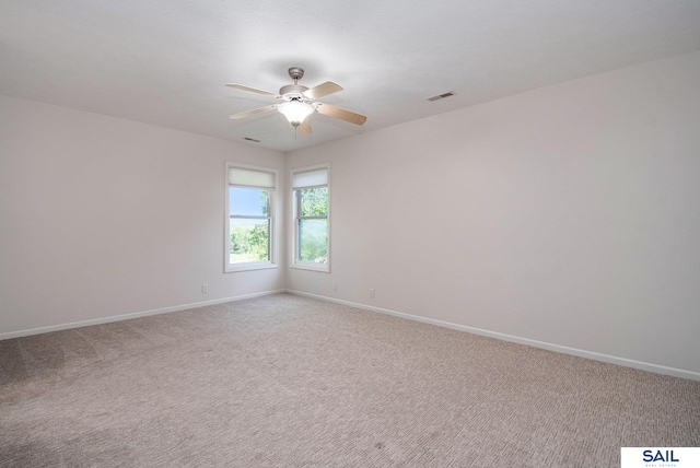 carpeted spare room featuring ceiling fan and baseboards