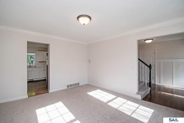unfurnished living room featuring dark carpet, ornamental molding, stairs, and baseboards